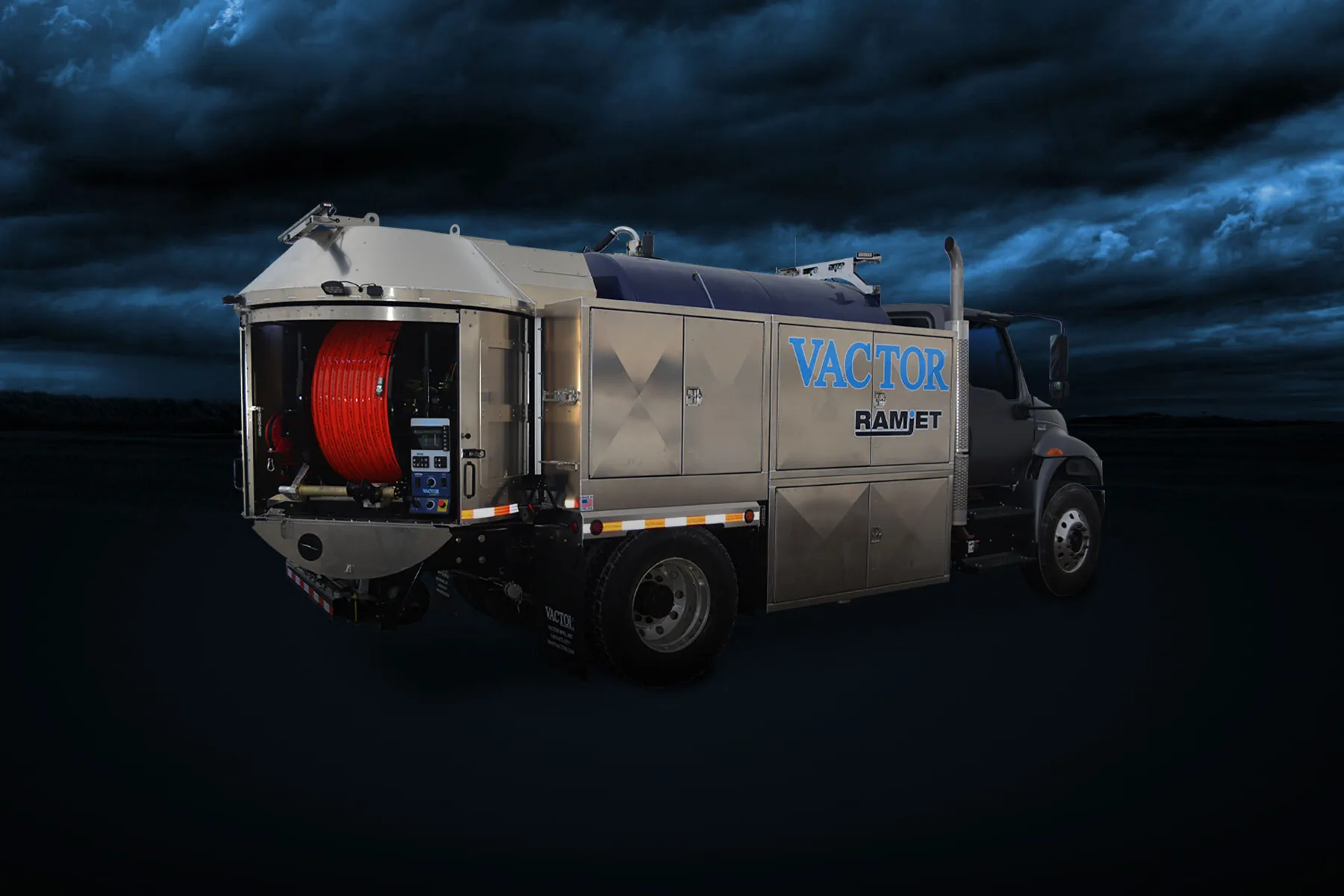 A stainless steel Vactor Ramjet truck with a large red hose reel, set against a dramatic stormy sky.