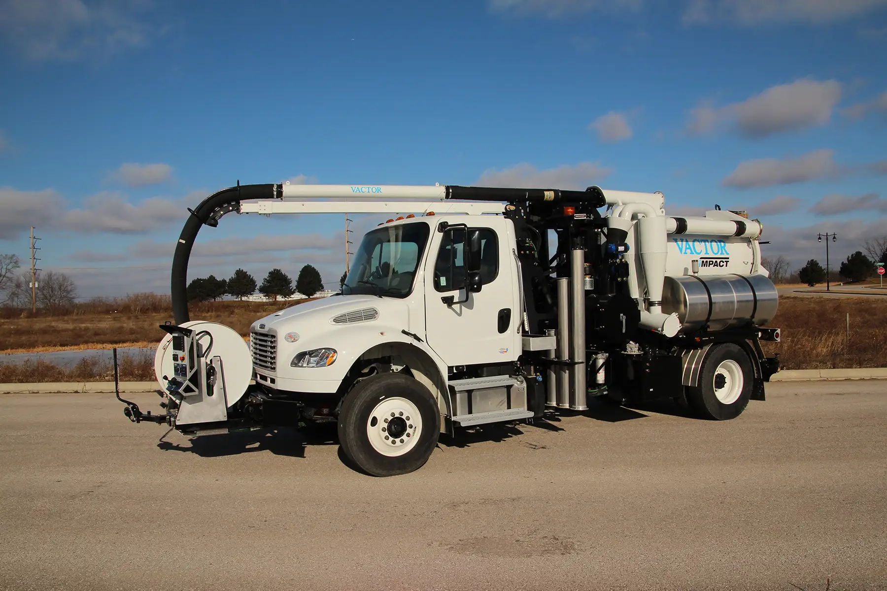A white Vactor Impact street sweeper truck parked on asphalt under a partly cloudy sky.